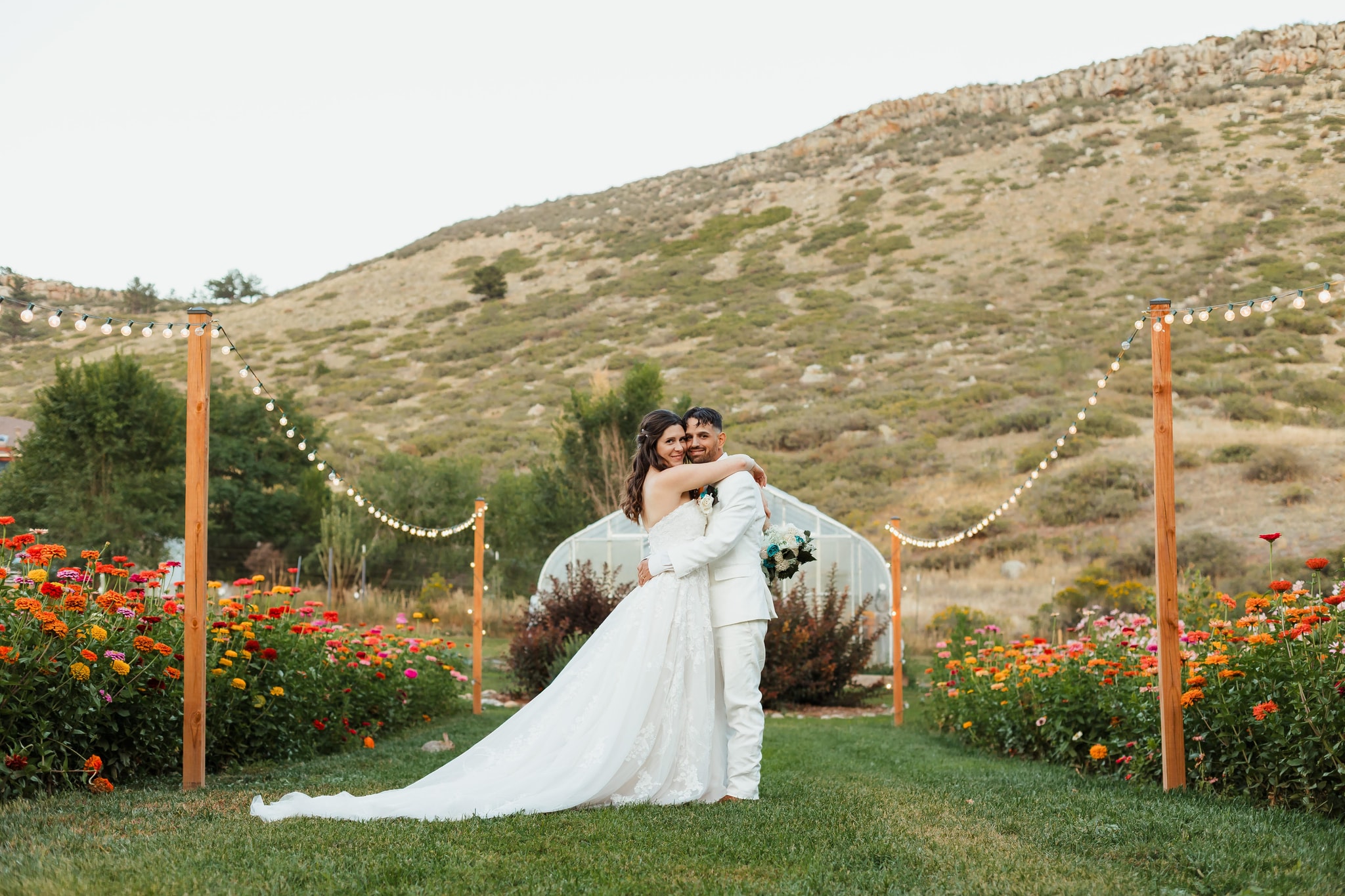 Bride and groom embracing in a flower garden with a mountain backdrop — Northern Colorado wedding by Karismatic Photos