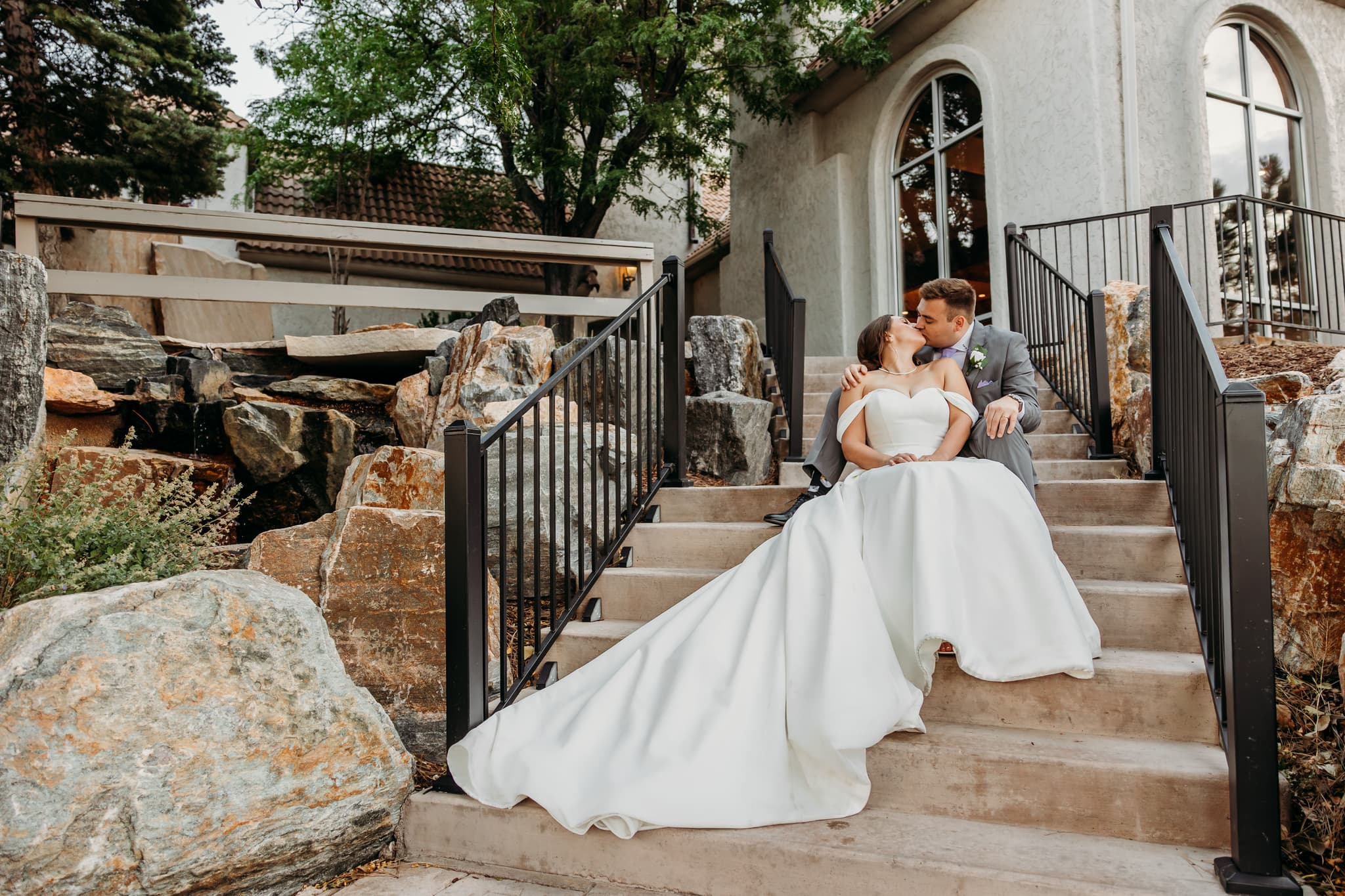 Bride and groom kissing on garden steps — Colorado wedding by Karismatic Photos