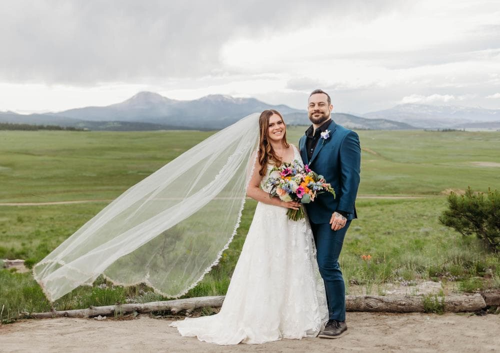 Bride and groom sharing first kiss at outdoor wedding ceremony Colorado
